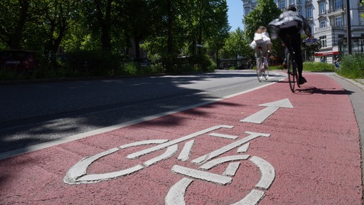 Radfahrer fahren auf der mit roter Farbe markierten Fahrradspur am Stern. 