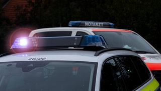 Ein Polizei- und ein Notarztwagen stehen auf einer Straße.