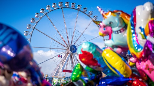 Ein Riesenrad ist hinter Luftballons zu sehen.