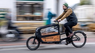 Ein Mann fährt auf einem Lastenrad