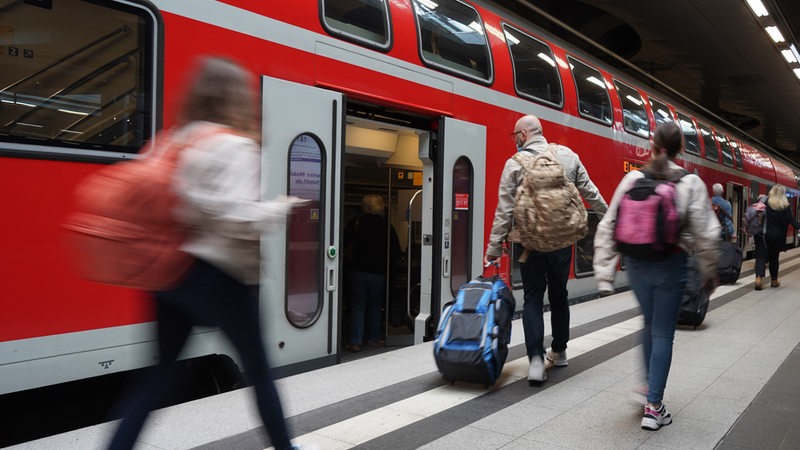 Menschen steigen in einen Zug ein und aus.