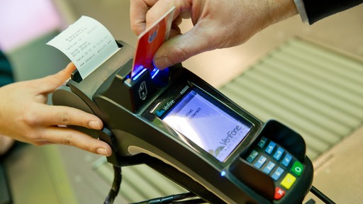 Eine Person steckt eine EC-Karte in ein Terminal.