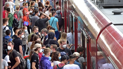 Viele Menschen, versuchen in einen Regionalzug zu gelangen. Es herrscht dichtes Gedränge.