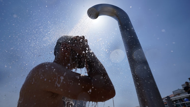 Ein Mann kühlt sich unter einer Dusche ab.