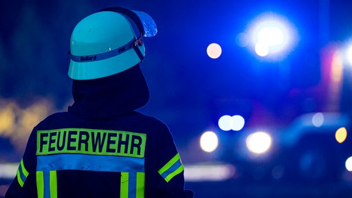 Ein Feuerwehrmann steht vor einem Feuerwehrfahrzeug.