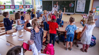 Eine Lehrerin steht vor einer ersten Klasse an der Tafel.