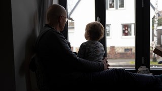 Vater und Kleinkind vertreiben sich die Zeit und schauen aus dem Fenster