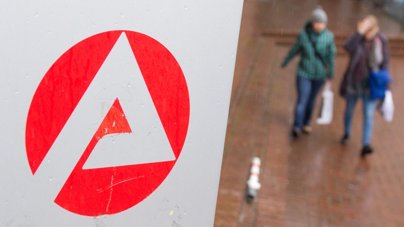 Zwei Frauen gehen an dem Logo der Bundesagentur für Arbeit in Hannover (Niedersachsen) vorbei. 