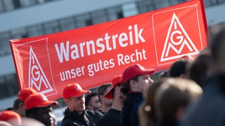 Teilnehmer einer Kundgebung der Gewerkschaft IG Metall halten während eines Warnstreiks ein Transparent mit der Aufschrift "Warnstreik unser gutes Recht" in die Höhe. 