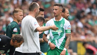 Ole Werner spricht am Feldesrand mit Marco Friedl.