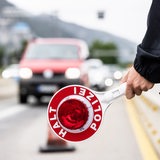 Ein Polizist hält auf einer Autobahn eine Kelle mit der Aufschrift "Halt Polizei" in der Hand. 