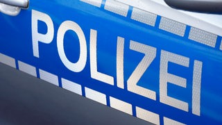 Polizei steht auf der Tür eines Autos. 