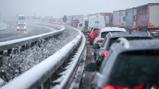 Autos stehen auf der verschneiten Autobahn im Stau. 