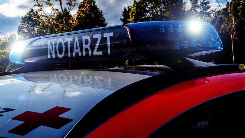 Auf einem Fahrzeug steht die Aufschrift "Notarzt". Außerdem blinkt ein Blaulicht.