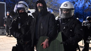 Polizisten führen bei der Räumung von Lützerath einen Demonstranten ab. 