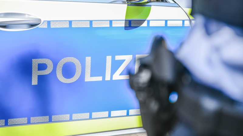 Ein Polizist steht vor einem Streifenwagen