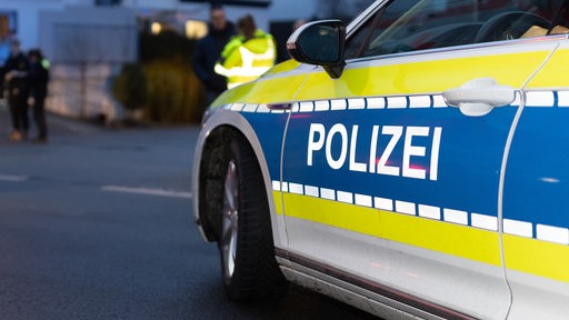 Ein Einsatzfahrzeug der Polizei, Streifenwagen, steht mit Blaulicht und Schriftzug an einem Verkehrsunfall. 