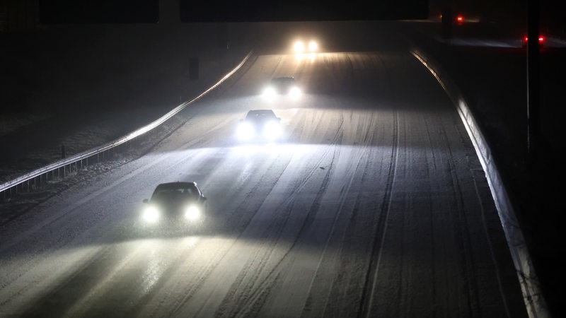 Autos fahren bei Schneefall auf der mit Schnee bedeckten Autobahn.