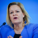 Bundesinnenministerin Nancy Faeser vor blauem Hintergrund.