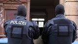 Zwei Polizisten stehen vor einem Hauseingang