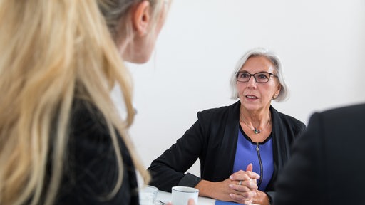 Eine ältere und eine jüngere Frau im Gespräch in einem Büro