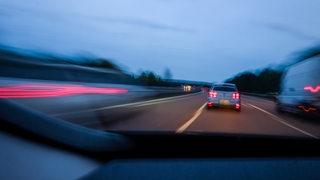 Autos fahren in der Dämmerung auf einer Autobahn.