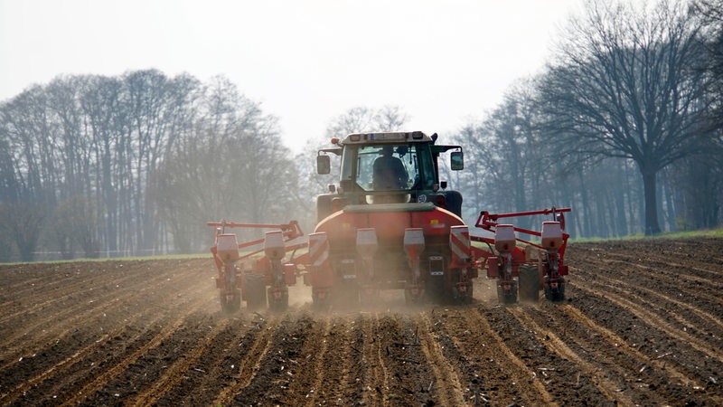 Ein Landwirt bearbeitet mit einer achtreihigen Einkorn-Saemaschine das Feld