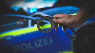 Ein Polizist hält Handsellen in der Hand.