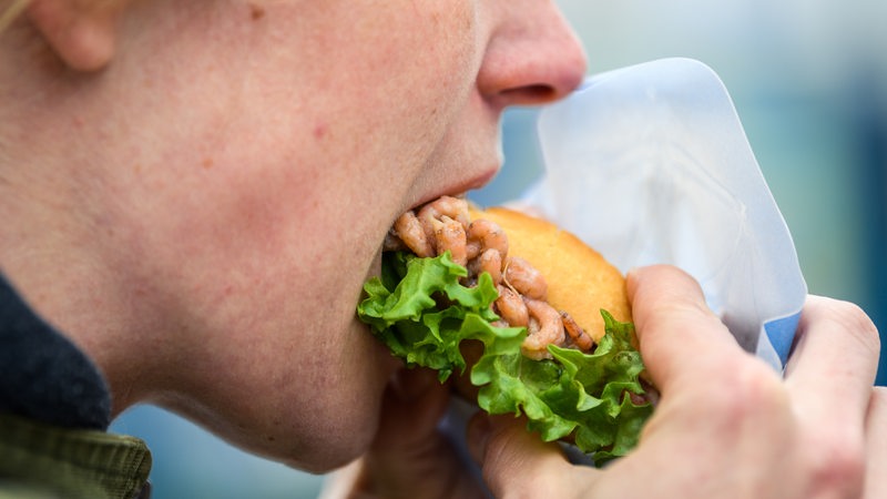 Eine Frau beißt in ein Krabbenbrötchen.