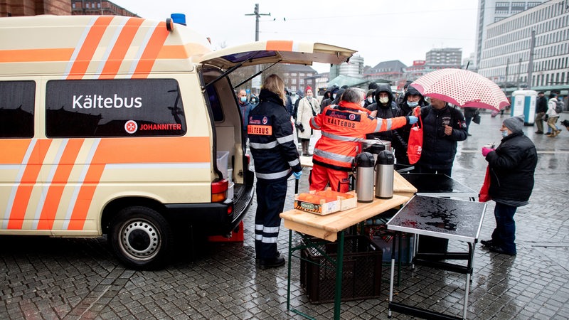 Karin Stelljes, Teamleiterin beim Kältebus der Johanniter, reicht an Heiligabend auf dem Vorplatz am Hauptbahnhof eine warme Mahlzeit an einen bedürftigen Menschen.