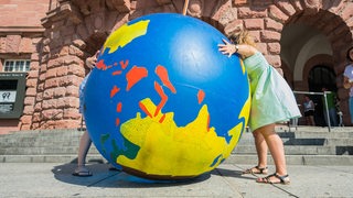 Frauen umarmen eine aufblasbare Erdkugel