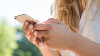 Eine junge Frau benutzt ihr Smartphone.