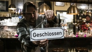 Ein Gastronom hängt ein Geschlossen-Schild in die Tür (Symbolfoto)