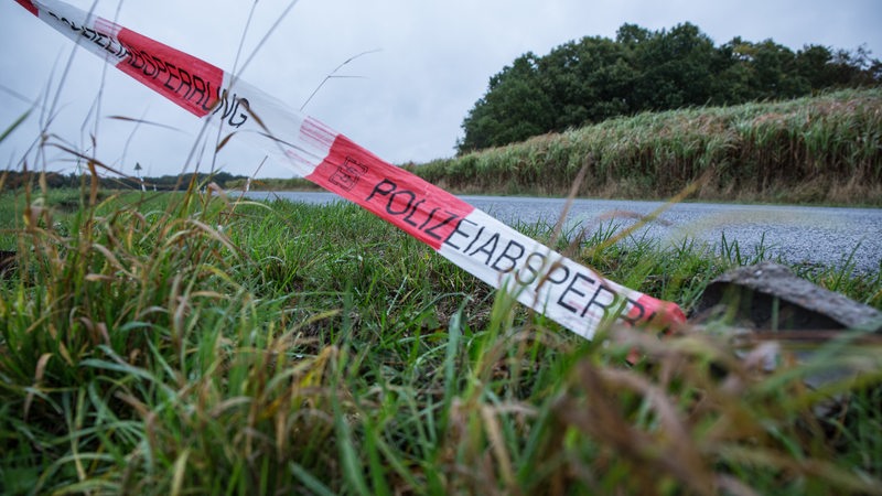 An einem Fluss flattert ein Absperrband mit der Aufschrift "Polizeiabsperrband".