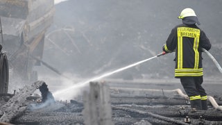 Ein Feuerwehrmann löscht den Brand einer Lagerhalle in Bremen.