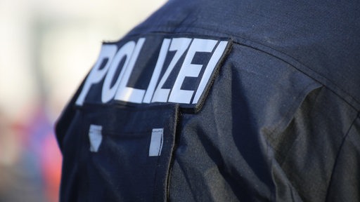 Auf der Uniform eines Polizisten steht "Polizei".