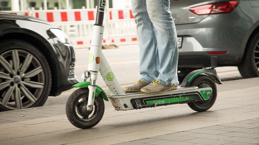 Eine Frau fährt auf einem Line-Scooter an Pkw vorbei (Archivbild)