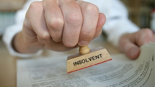 Ein Mann hält einen Stempel mit der Aufschrift "Insolvent" in der Hand