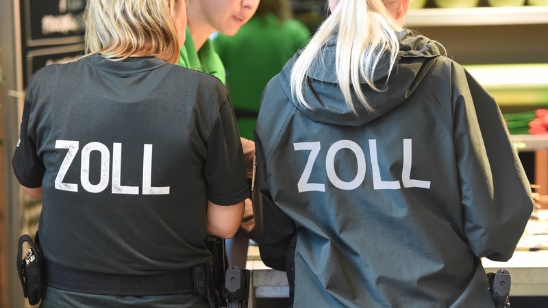 Zollbeamte kontrollieren Mitarbeiter in Einzelhandelsunternehmen und Gaststätten in einem Einkaufszentrum.