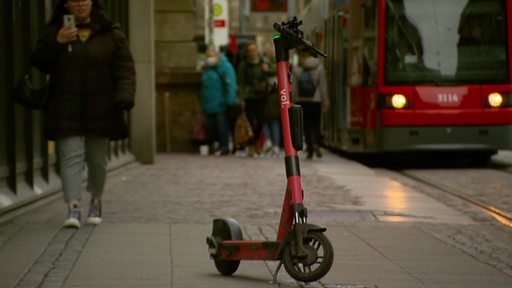 Ein E-Roller und im Hintergrund eine Straßenbahn.