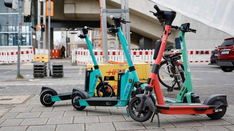 E-Scooter stehen auf einem Bürgersteig.