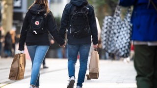 Passanten mit Einkaufstüten laufen durch die Innenstadt.