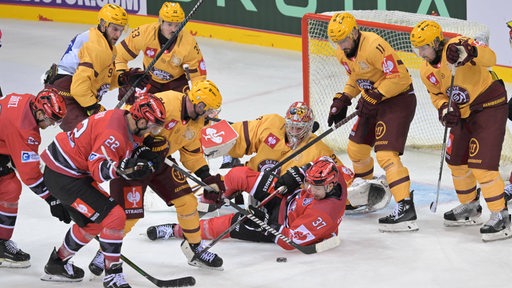 Eishockey-Spieler der Fischtown Pinguins mit vollem Körpereinsatz, aber erfolglos vor dem Tor des Genfer Gegners.