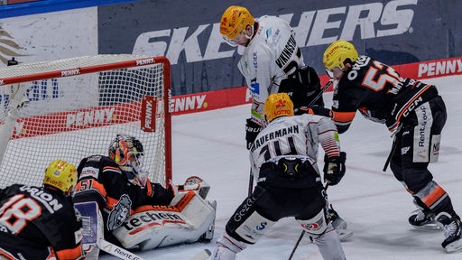 Eishockey-Spieler der Fischtown Pinguins versuchen den Puck trotz mehrerer Gegenspieler am Frankfurter Torwart vorbei ins Netz zu schieben.