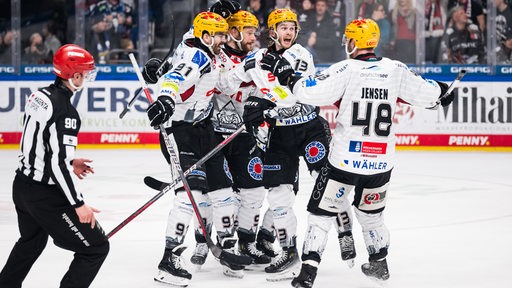 Eishockey-Spieler der Fischtown Pinguins liegen sich nach einem Tor jubelnd in den Armen.