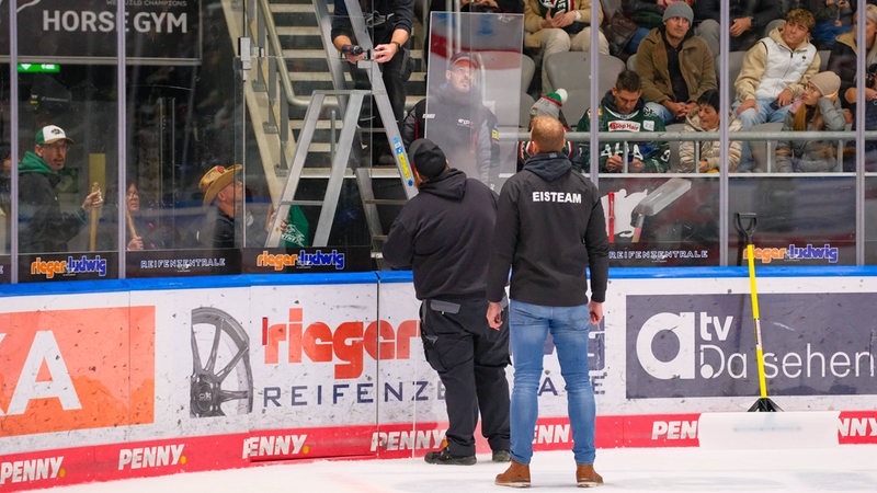 In der Eishockey-Partie zwischen den Fischtown Pinguins und den Augsburger Panthern muss an der Bande eine zerbrochene Schutzscheibe von Helfern ersetzt werden.