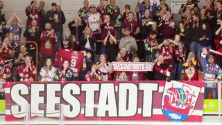 Fans der Fischtown Pinguins bejubeln ihre Mannschaft beim Auswärtsspiel in Wolfsburg auf der Tribüne.