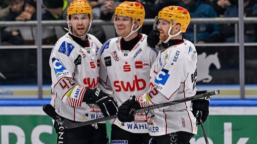 Die Eishockey-Spieler Matthew Abt, Phillip Bruggisser und Max Goertz von den Fischtown Pinguins bejubeln einen Treffer auf dem Eis.