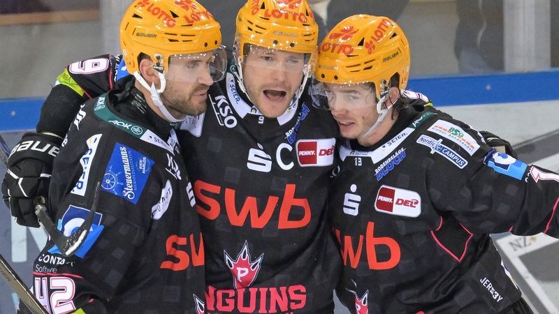 Die Eishockey-Spieler Jan Urbas, Matthew Abt und Ziga Jeglic von den Fischtown Pinguins kommen zu Jubel zusammen nach einem Tor