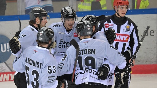 Eishockey-Spieler der Kölner Haie kommen jubelnd auf dem Eis zusammen nach einem Treffer gegen die Fischtown Pinguins.